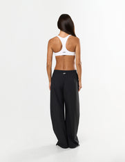 Back view of model wearing STAX. Stella Pants in black with STAX. Metal plate logo and white STAX. sports bra