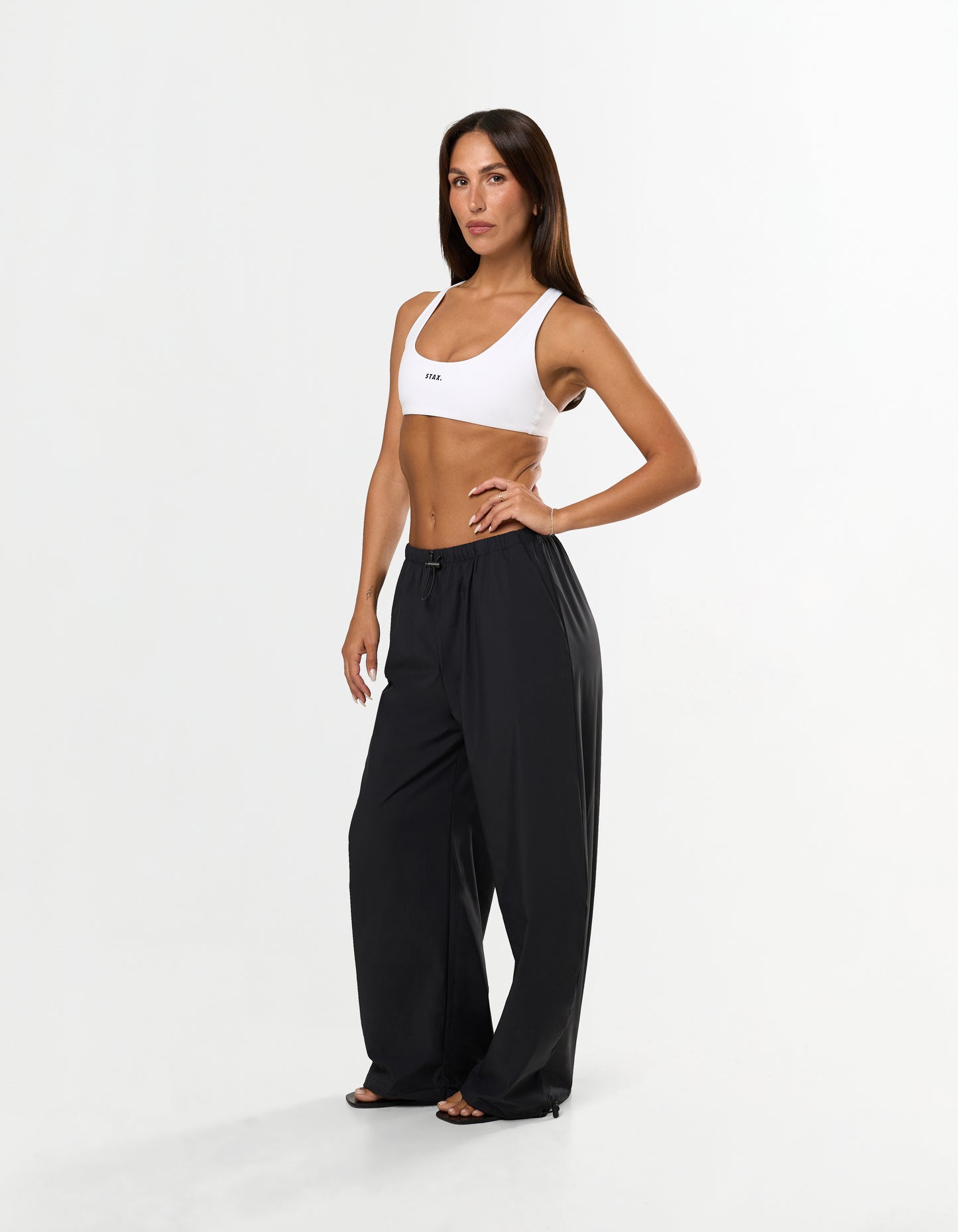 Front view of model wearing STAX. Stella Pants in black with Elastic and toggle drawcord waistband and white STAX. sports bra