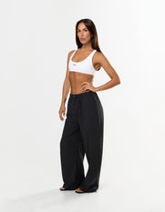 Front view of model wearing STAX. Stella Pants in black with Elastic and toggle drawcord waistband and white STAX. sports bra