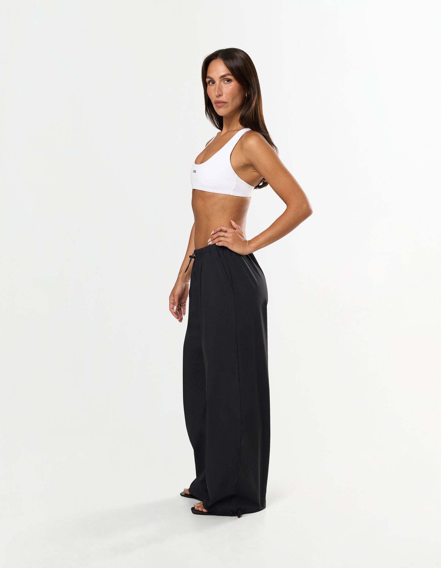 Side view of model wearing STAX. Stella Pants in black styled high waist with elastic and toggle drawstring 