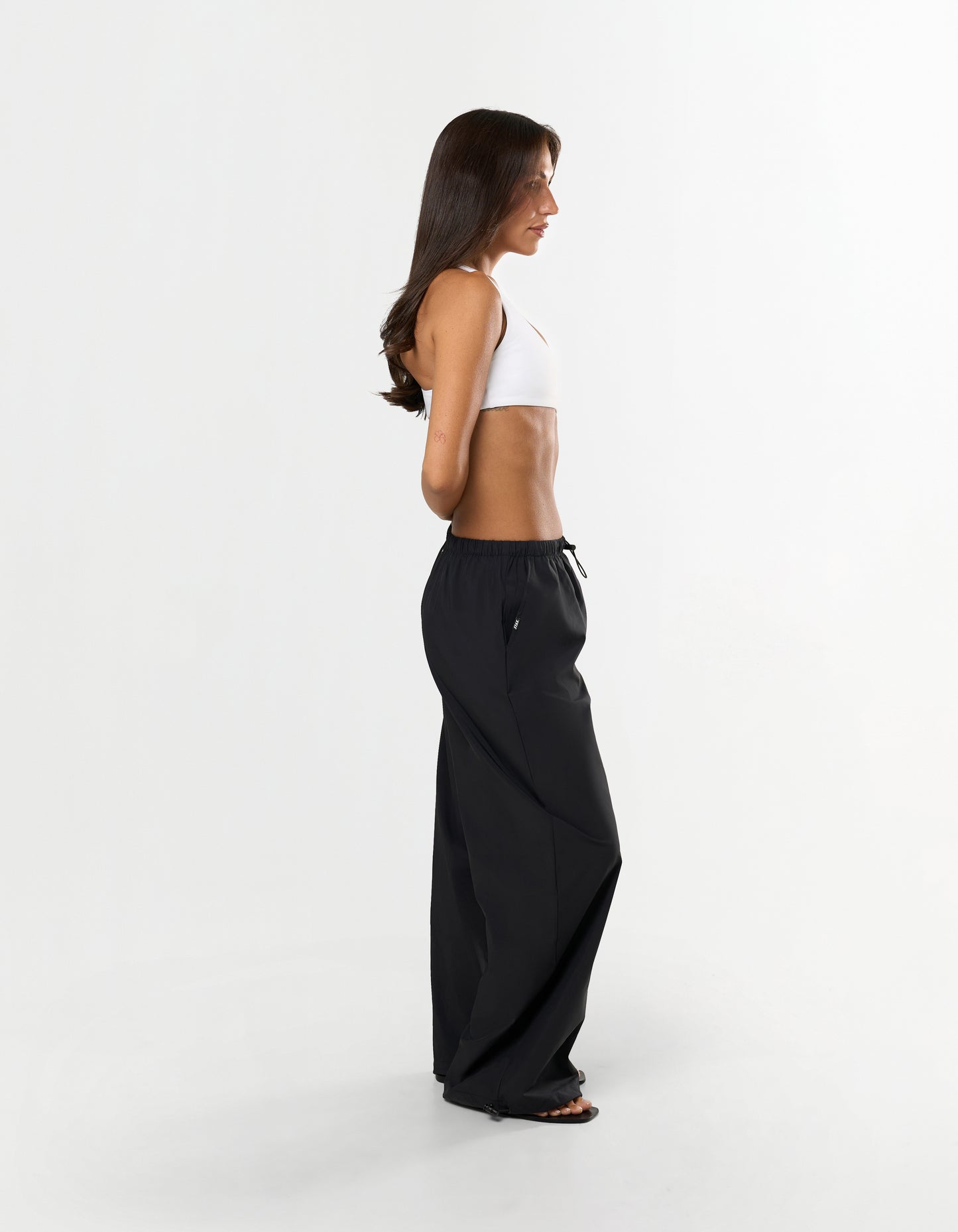 Side view of model wearing STAX. Stella Pants in black styled low waist with elastic and toggle drawstring 