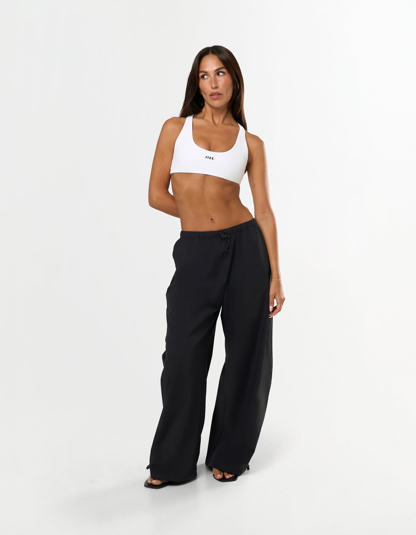 Front view of model wearing STAX. Stella Pants in black showing Toggle drawcord on leg opening