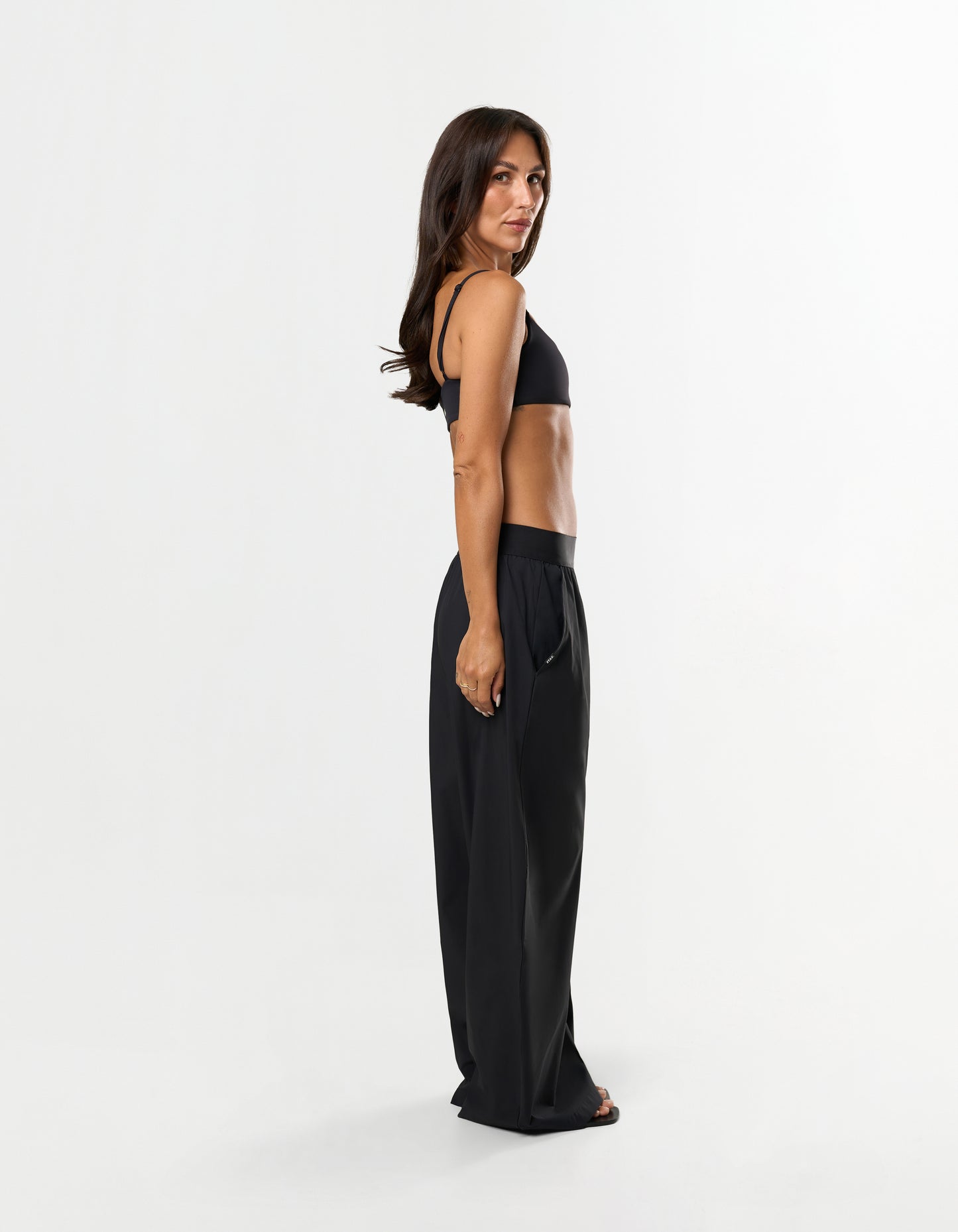 Front view of model wearing STAX. Gigi Pants in black showing outer elastic waistband design and relaxed straight leg fit