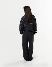 Back view of model wearing STAX. Woven Track Jacket in black with matching Track Pants