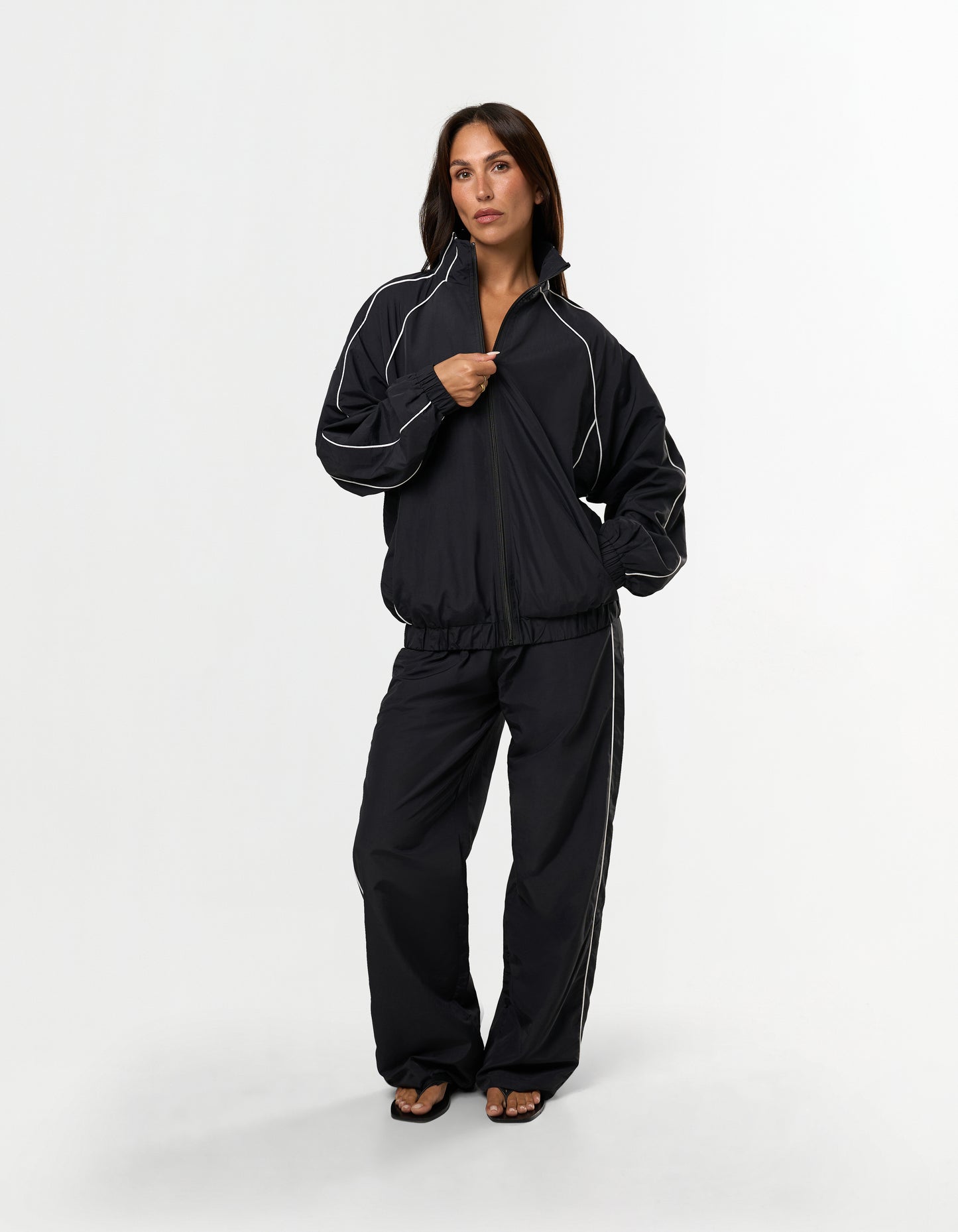 Front view of model wearing STAX. Woven Track Jacket zipped up with matching track pants