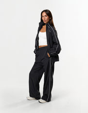 Front view of model wearing STAX. Woven Track Jacket in black with matching Track Pants