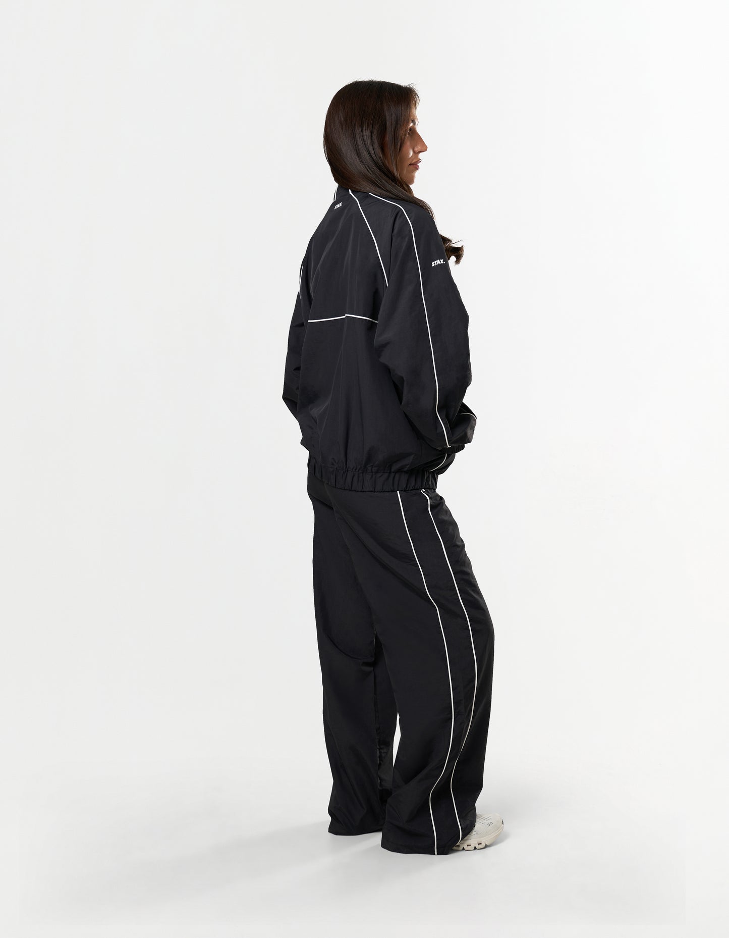 Side profile of STAX. Woven Track Pants in black showing slouched fit