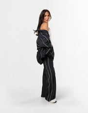 Side profile of STAX. Woven Track Jacket over the shoulder with matching woven track pants 