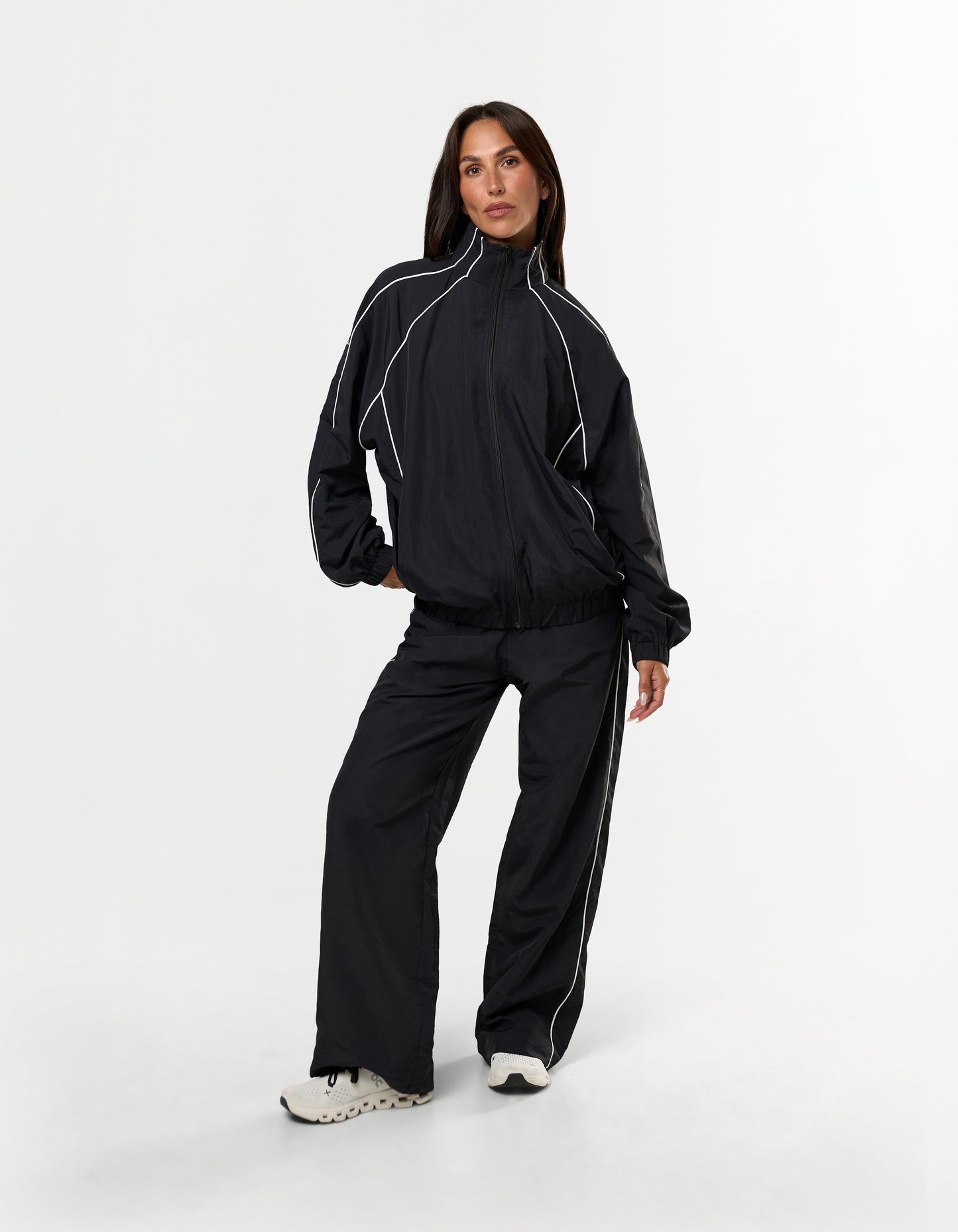 Front view of model wearing STAX. Woven Track Jacket showing off contrast piping detail