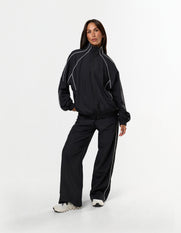 Front view of model wearing STAX. Woven Track Jacket showing off contrast piping detail