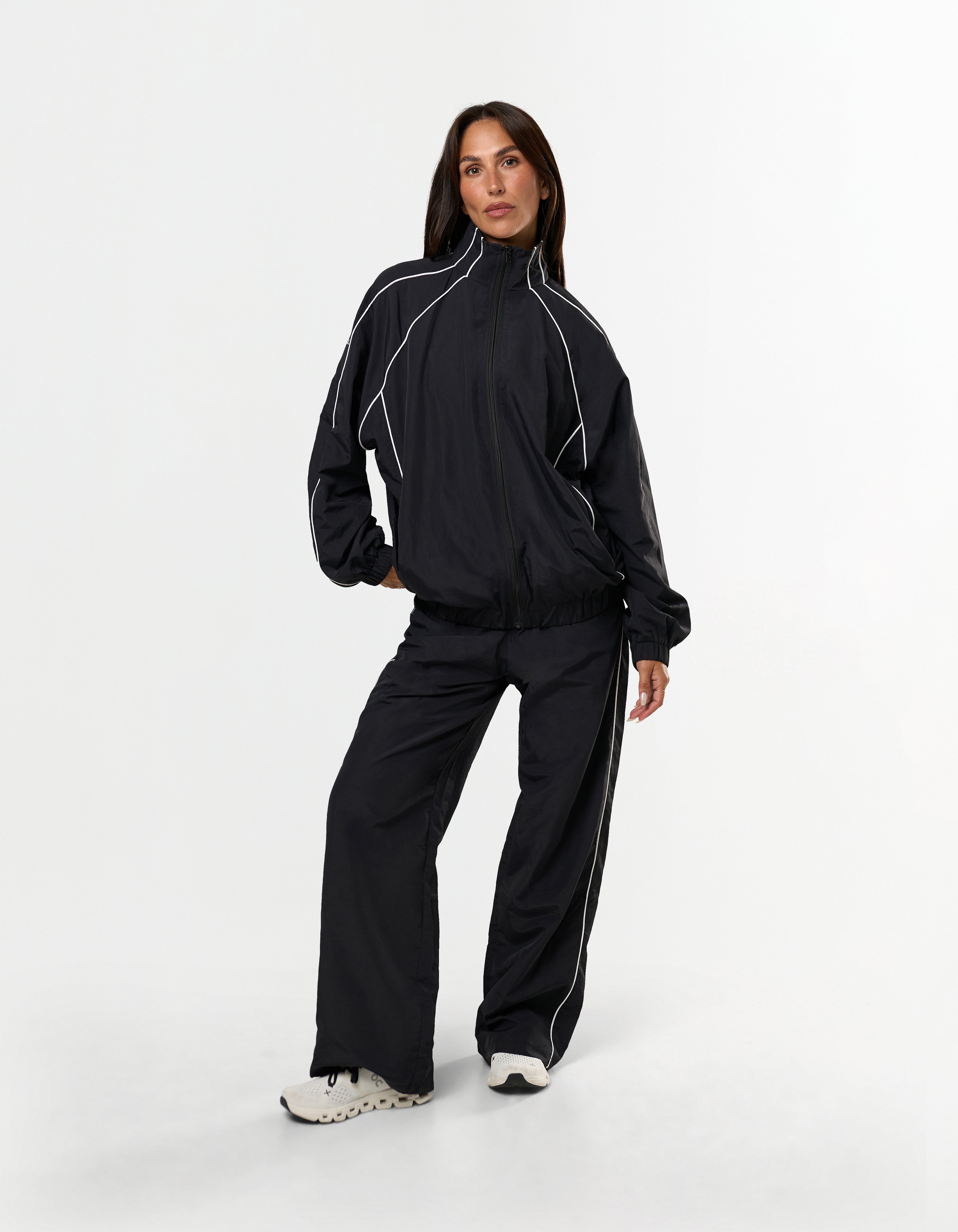 Front view of model wearing STAX. Woven Track Pants in Black with matching Woven Track Jacket showing contrast panelling 