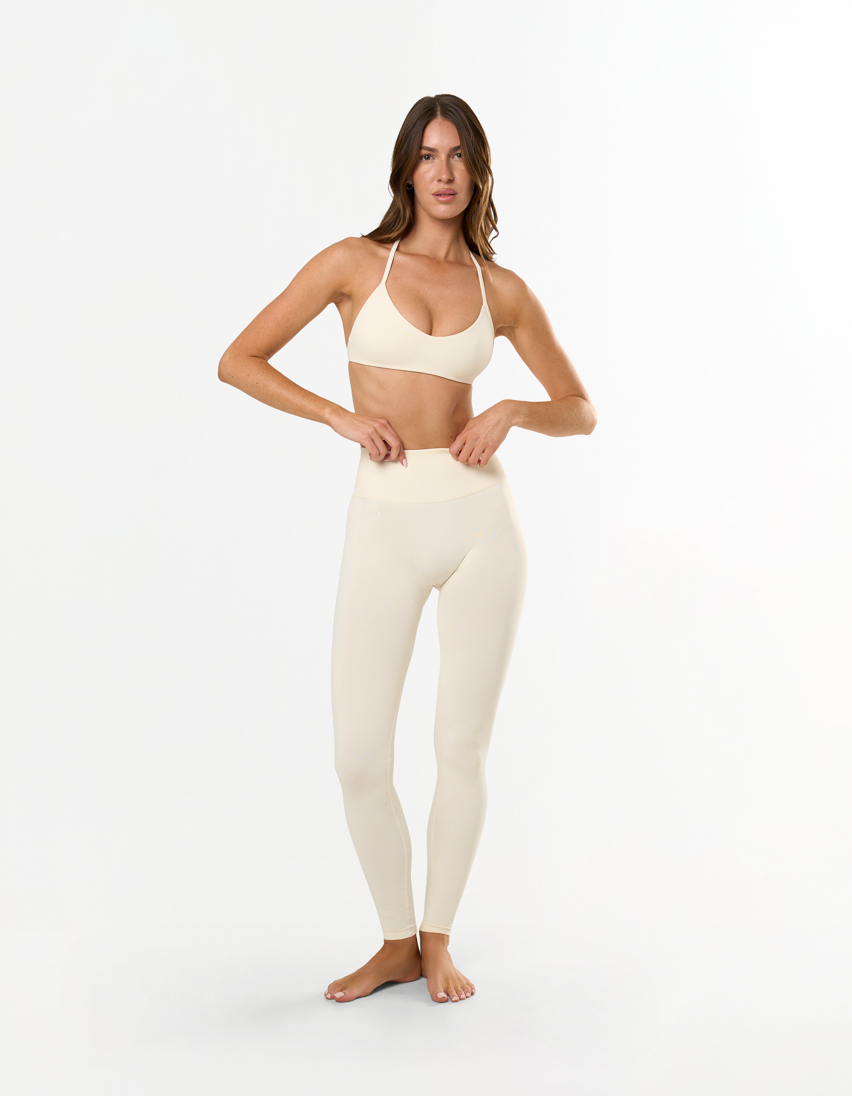Front view of model wearing STAX. Premium Seamless Skulpt Leggings in Cream with matching skulpt bralette in Cream