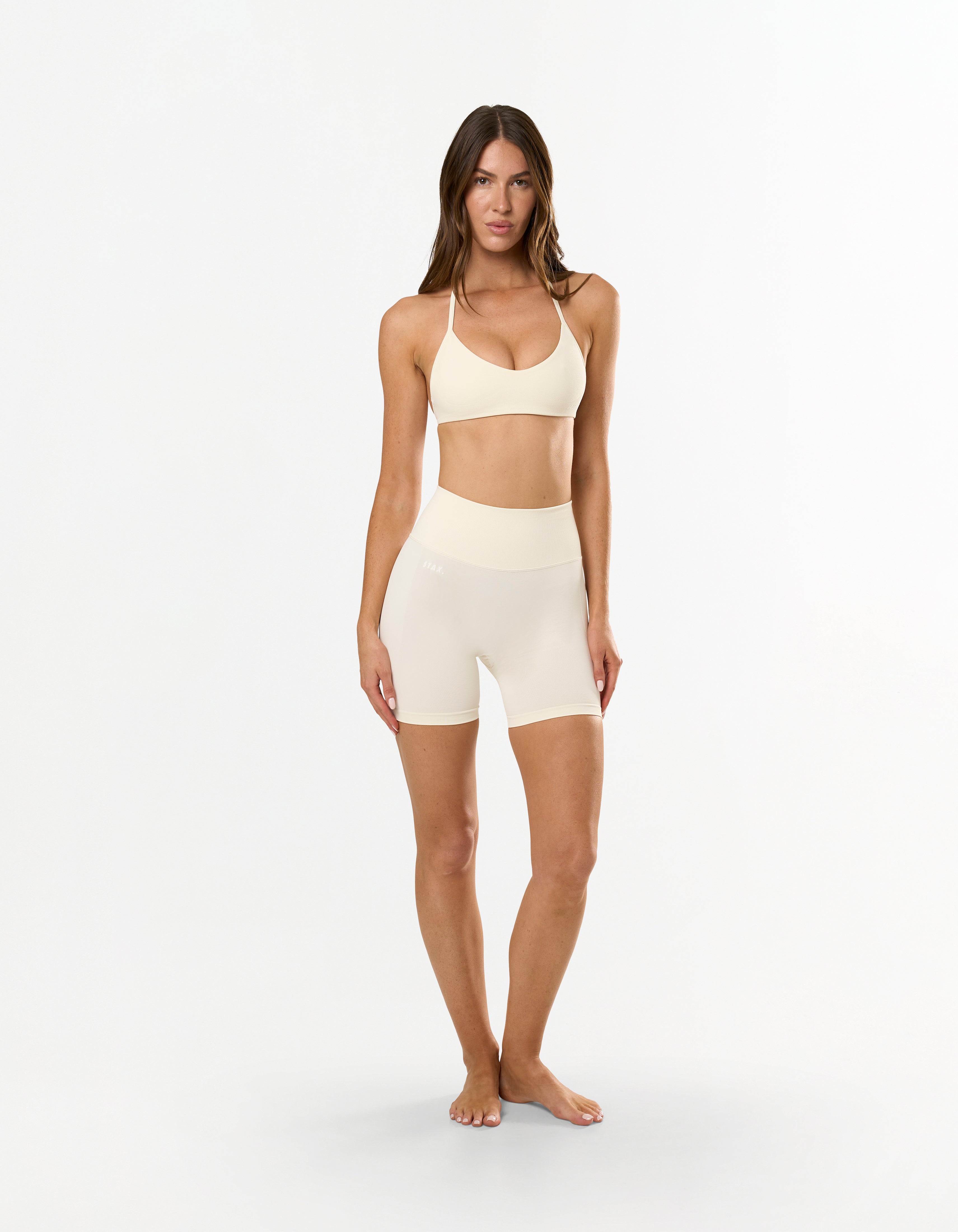 Front view of model wearing STAX. Premium Seamless Skulpt Midi Bike Shorts in Cream showing sleep compressive waistband design