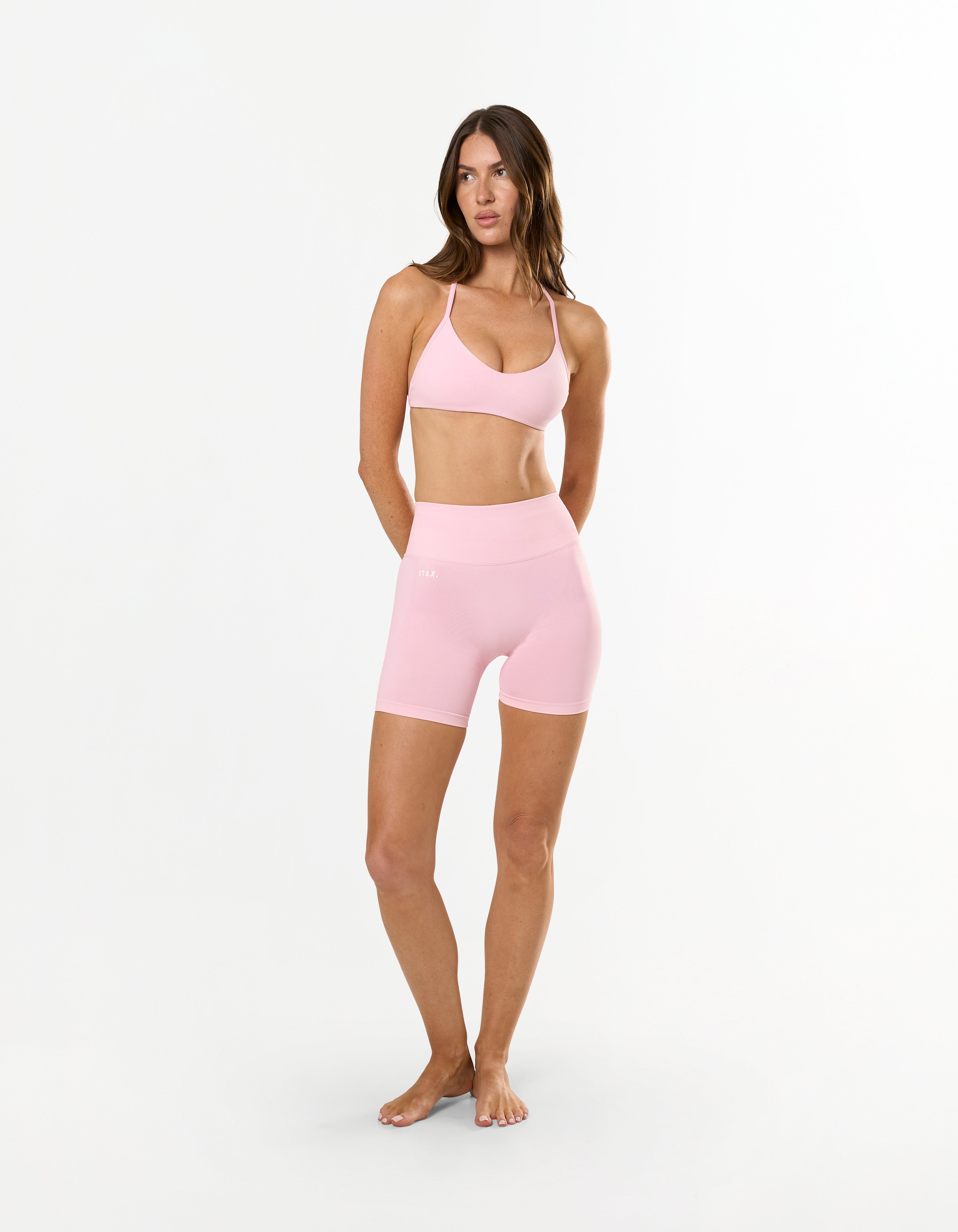 Front view of model wearing STAX. Premium Seamless Skulpt Bralette in Pink with matching skulpt midi bike shorts 