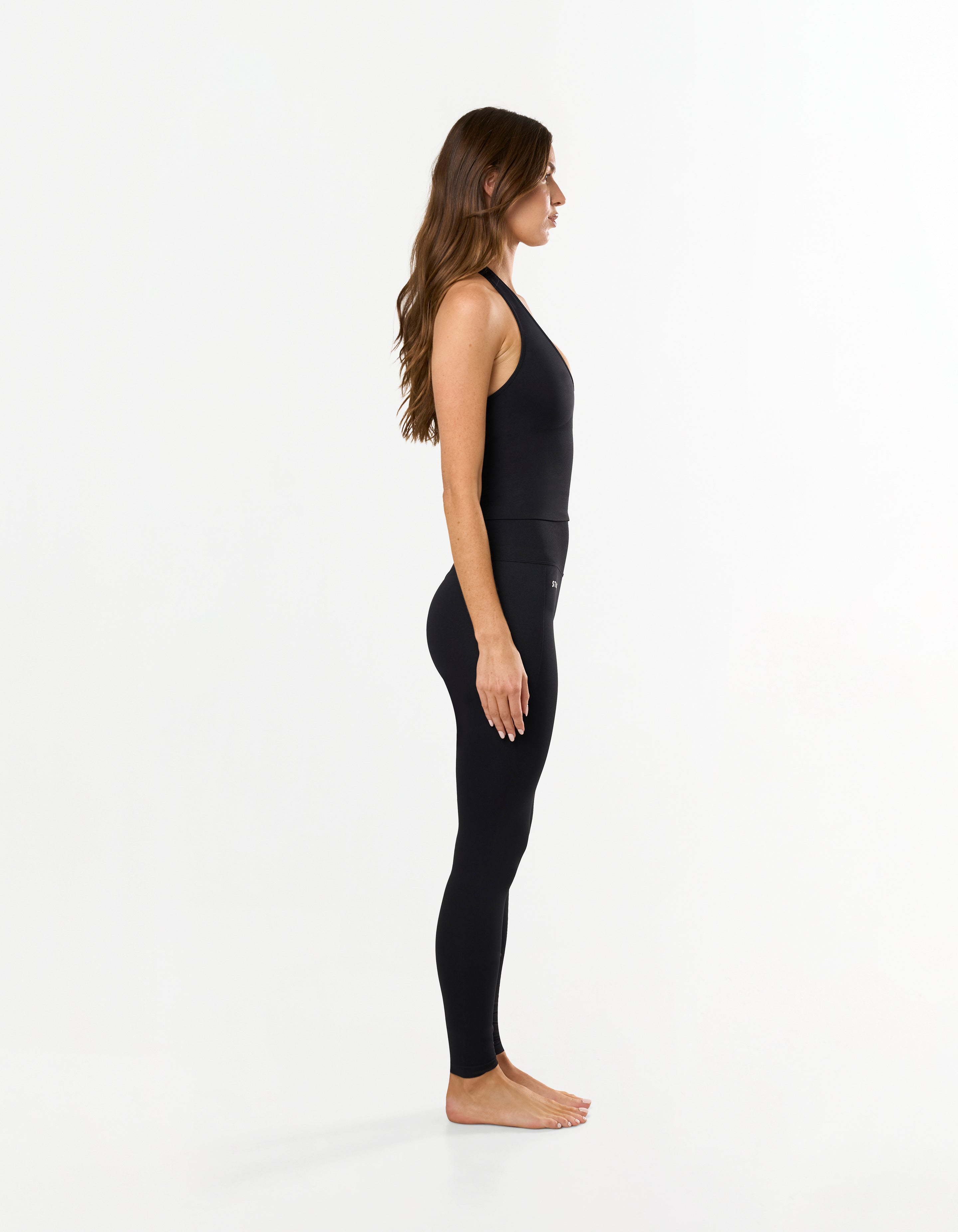 Side view of model wearing STAX. Premium Seamless Skulpt Tights in Black with matching Skulpt halter tank in black