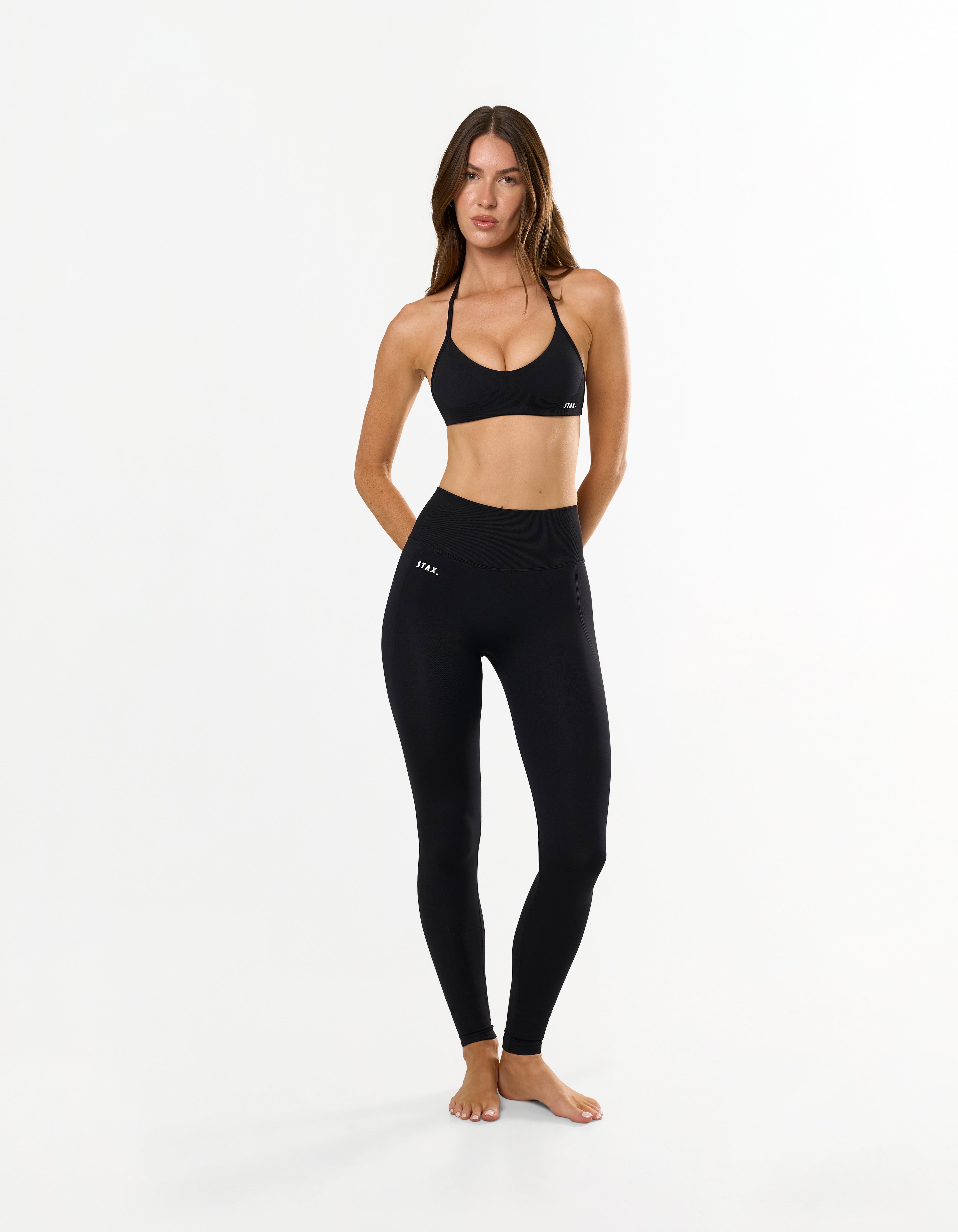 Front view of model wearing STAX. Premium Seamless Skulpt Tights in Black showing premium nylon spandex fabric with printed silicone logo