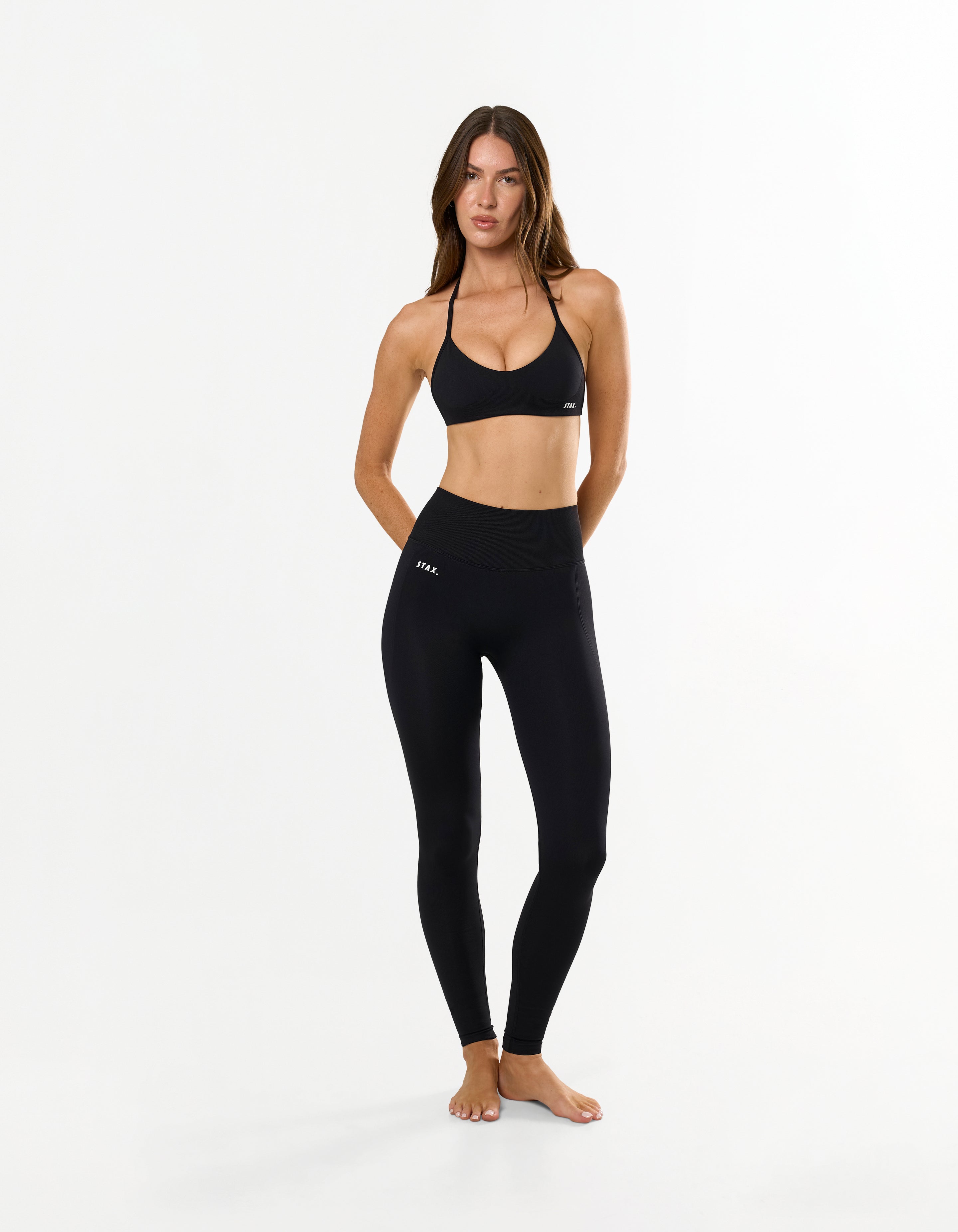 Front view of model wearing STAX. Premium Seamless Skulpt Tights in Black showing premium nylon spandex fabric with printed silicone logo