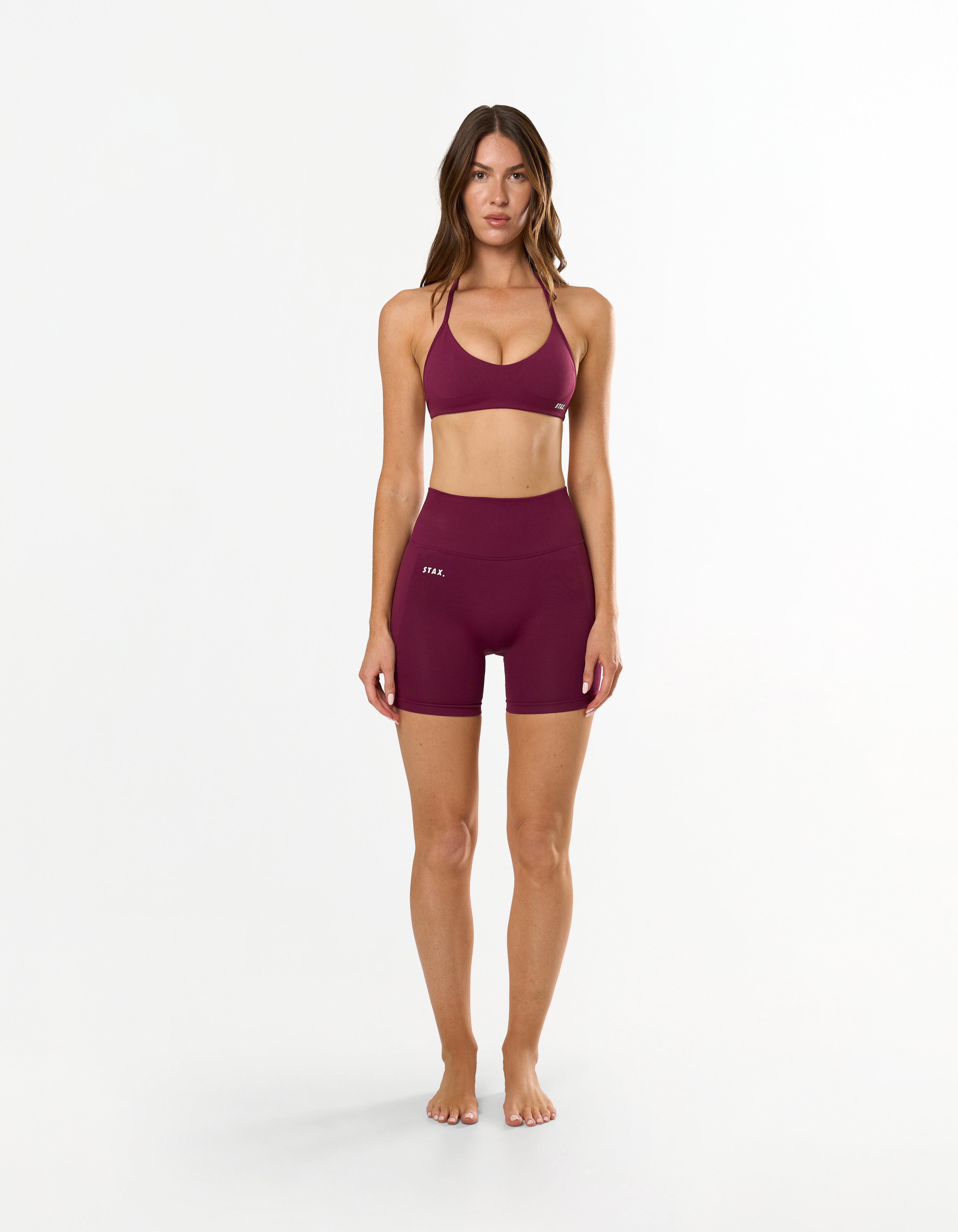 Front profile of model wearing STAX. Premium Seamless Skulpt Midi Bike Shorts  in Burgundy showing flattering compressive fit