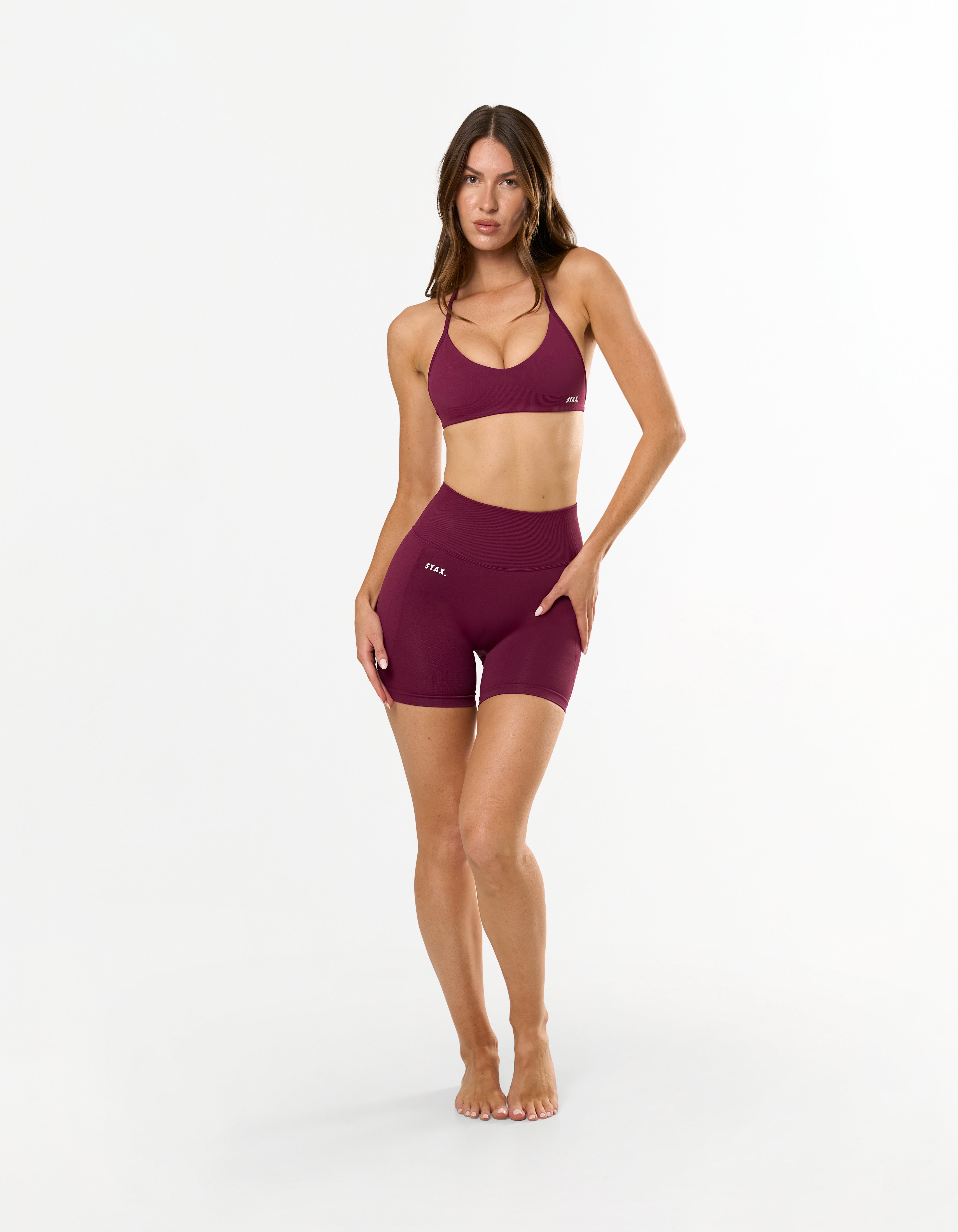 Front view of model wearing STAX. Premium Seamless Skulpt Bralette in Burgundy with matching bike shorts 