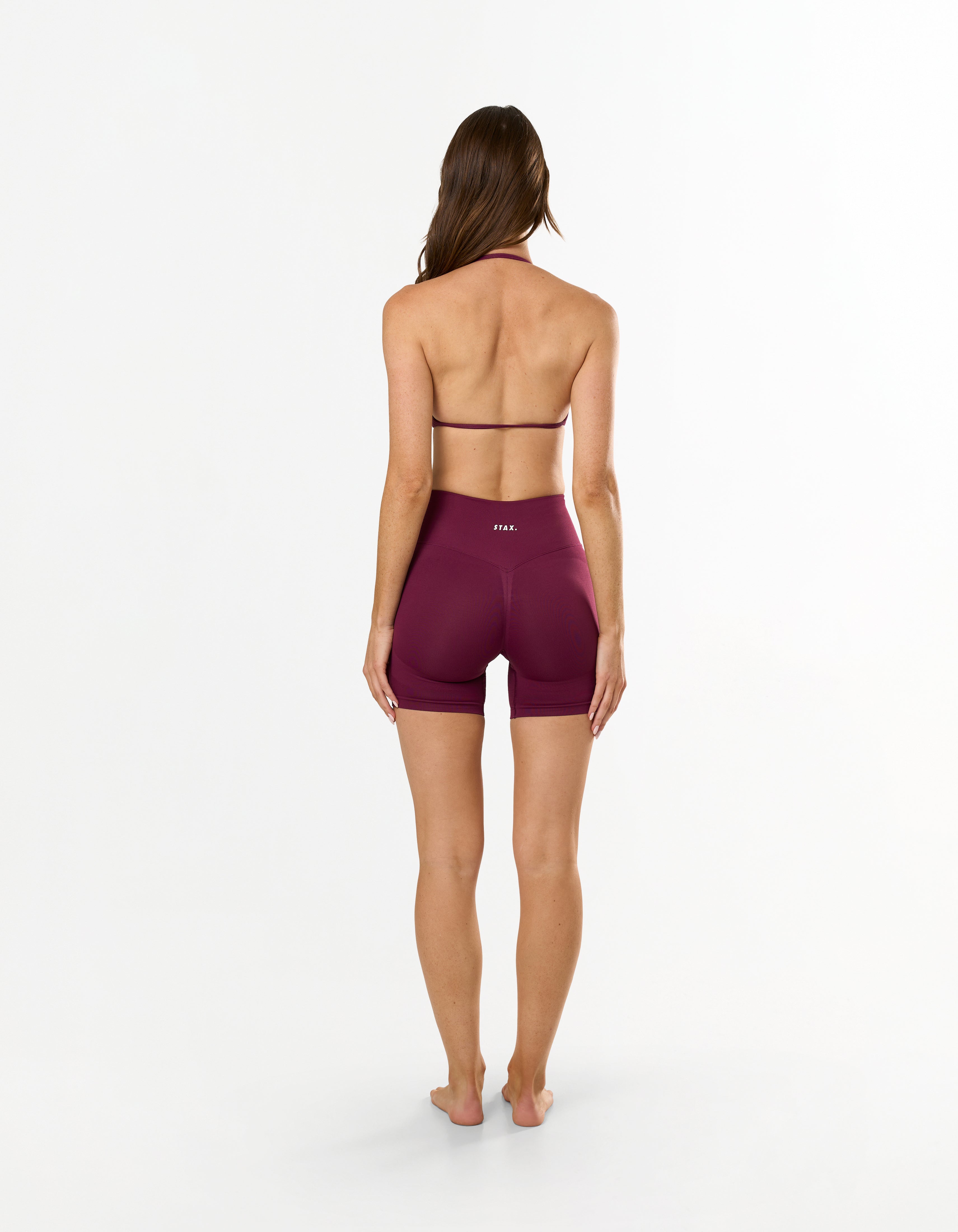 Back view of model wearing STAX. Premium Seamless Skulpt Midi Bike Shorts   in Burgundy showing flattering invisible scrunch detail  