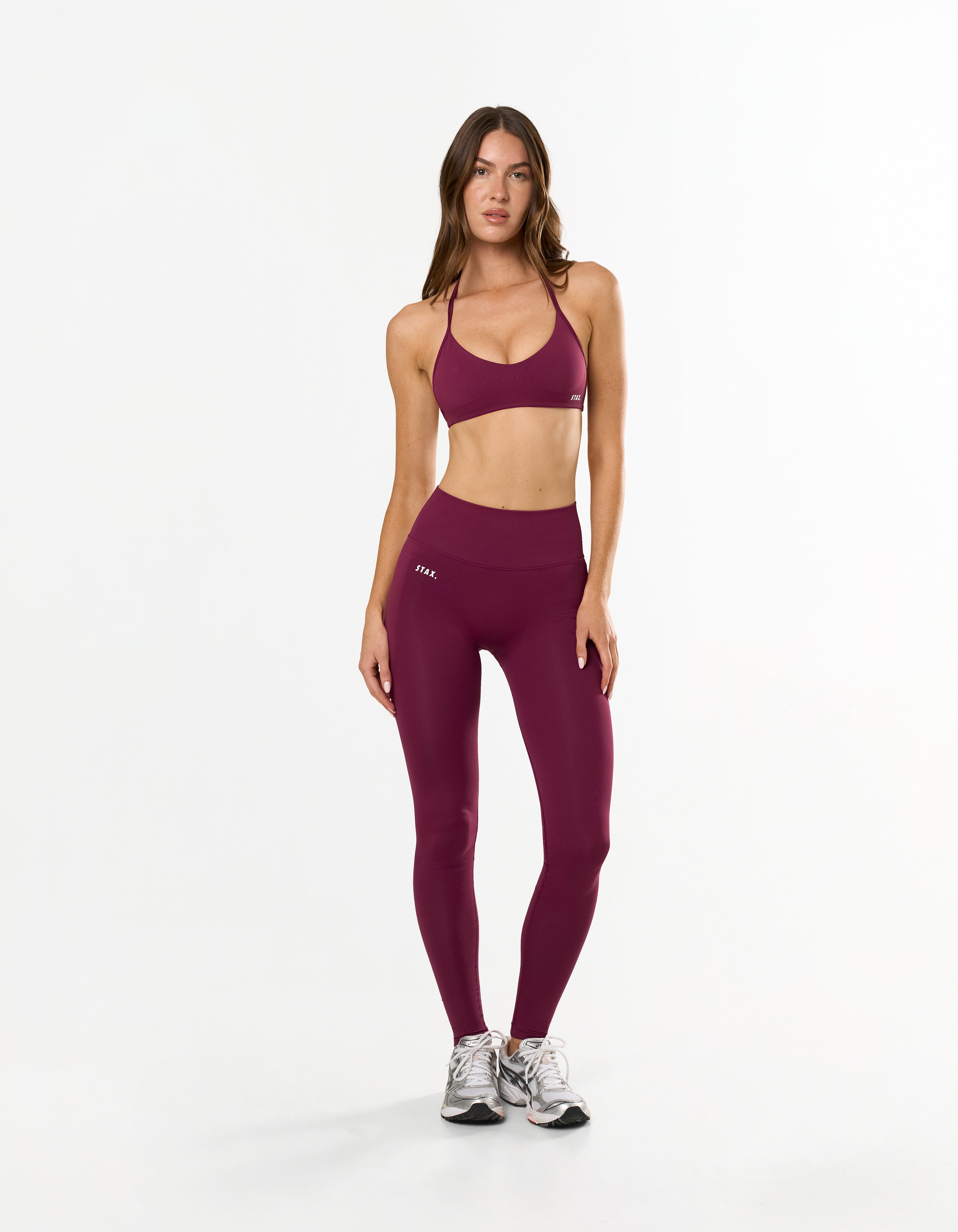 Front view of model wearing STAX. Premium Seamless Skulpt Tights in Burgundy showing premium nylon spandex fabric with printed silicone logo