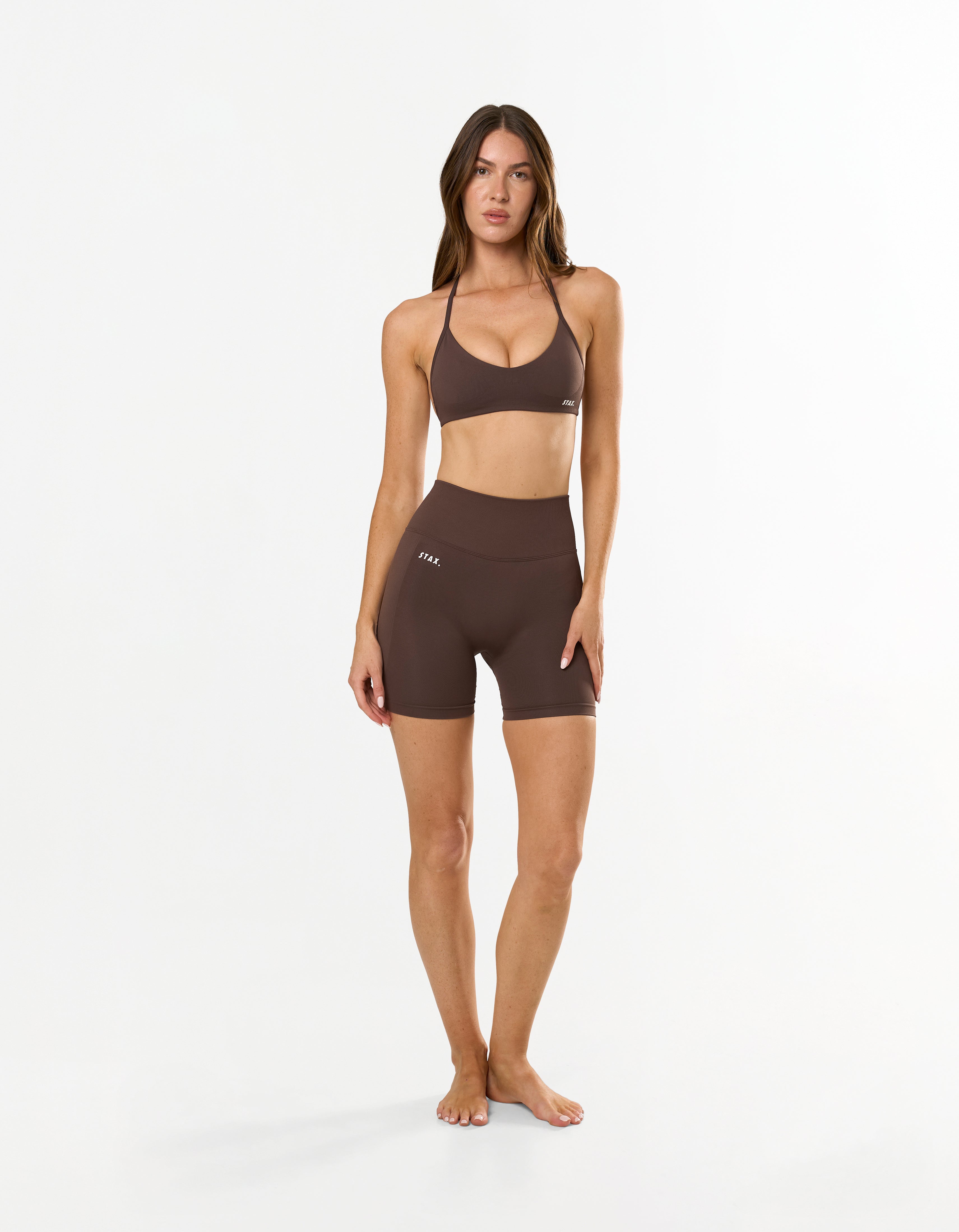 Front profile of model wearing STAX. Premium Seamless Skulpt Midi Bike Shorts in Brown with compressive curve enhancing fit 