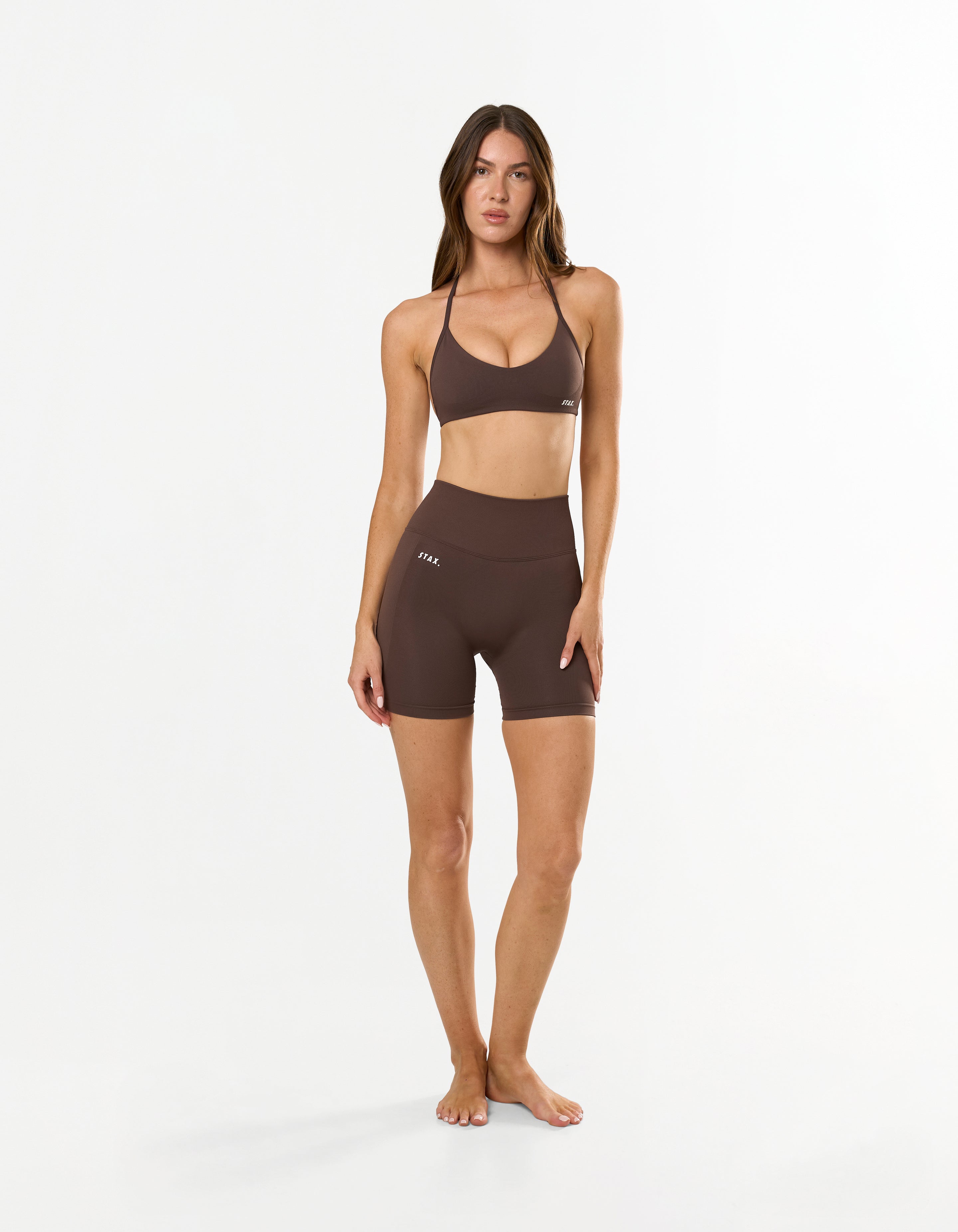 Front profile of model wearing STAX. Premium Seamless Skulpt Midi Bike Shorts in Brown with compressive curve enhancing fit 