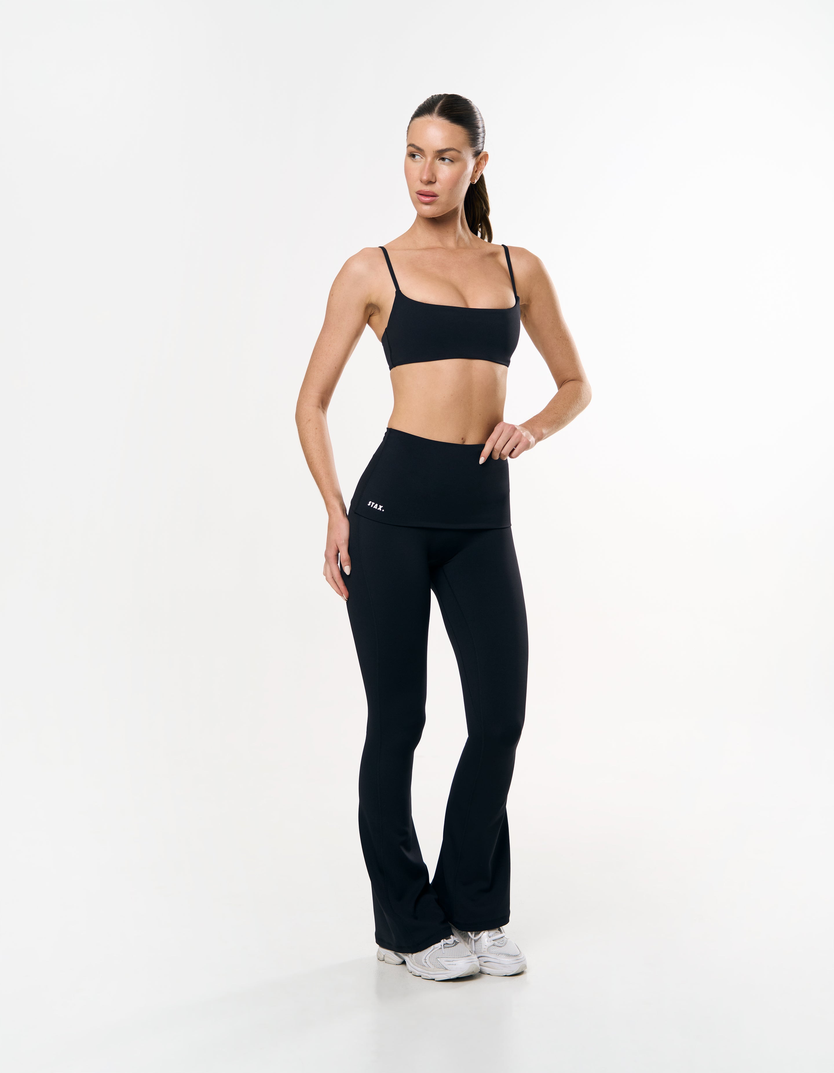 Front view of model wearing STAX. Fold over flares in black showing white logo detailing