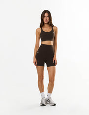 Front profile of model wearing STAX. NFS (No Front Seam) Midi Bike Shorts NANDEX™ in Espresso with matching Adapt sports bra with small white logos
