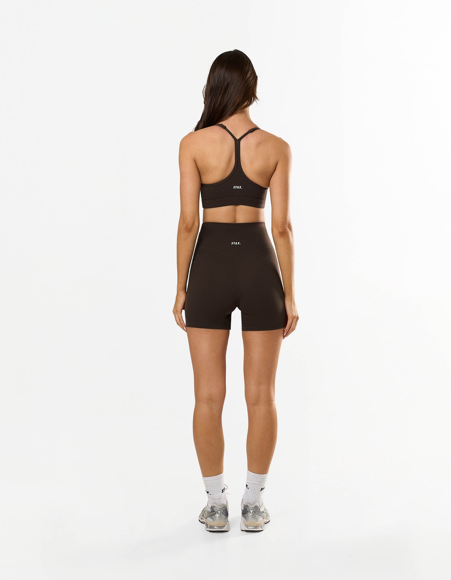 Back view of model wearing STAX. Strappy Crop NANDEX™ in Espresso with matching bike shorts showing flattering fit and small white logos