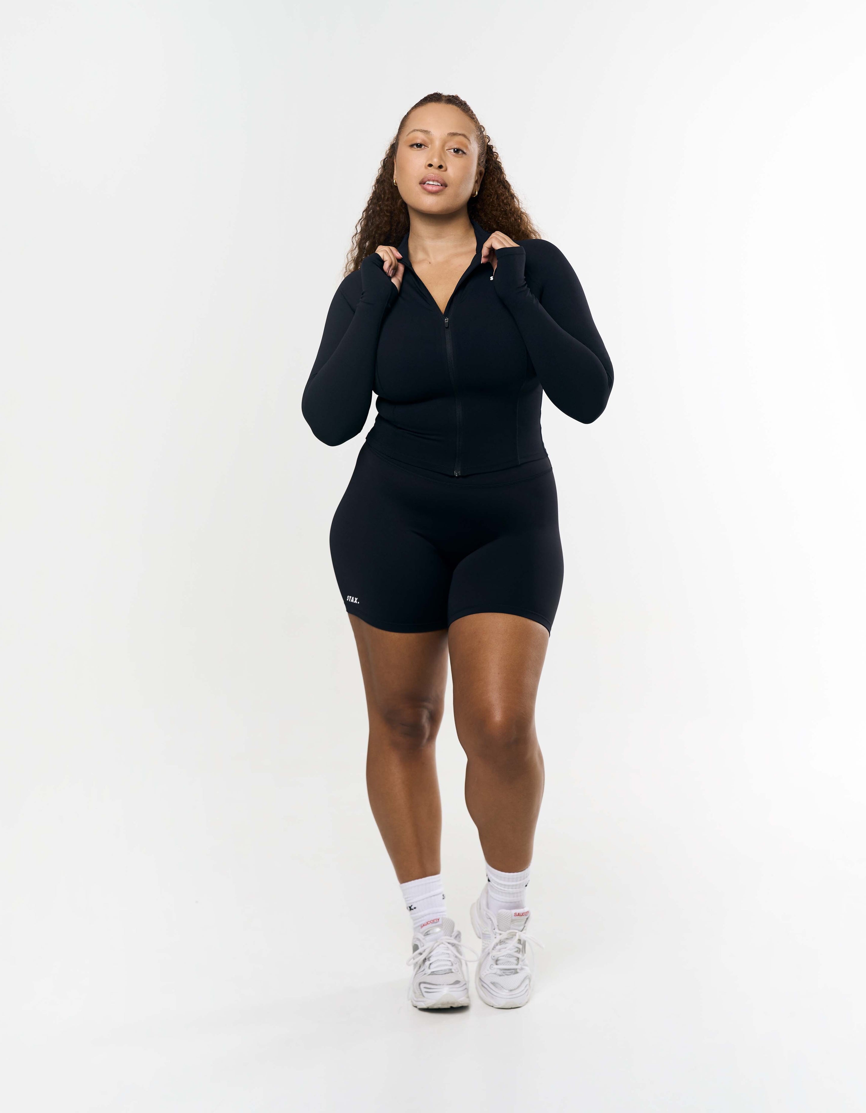 Front view of model wearing STAX. Active Zip Jacket Airlyte in Black with matching bike shorts